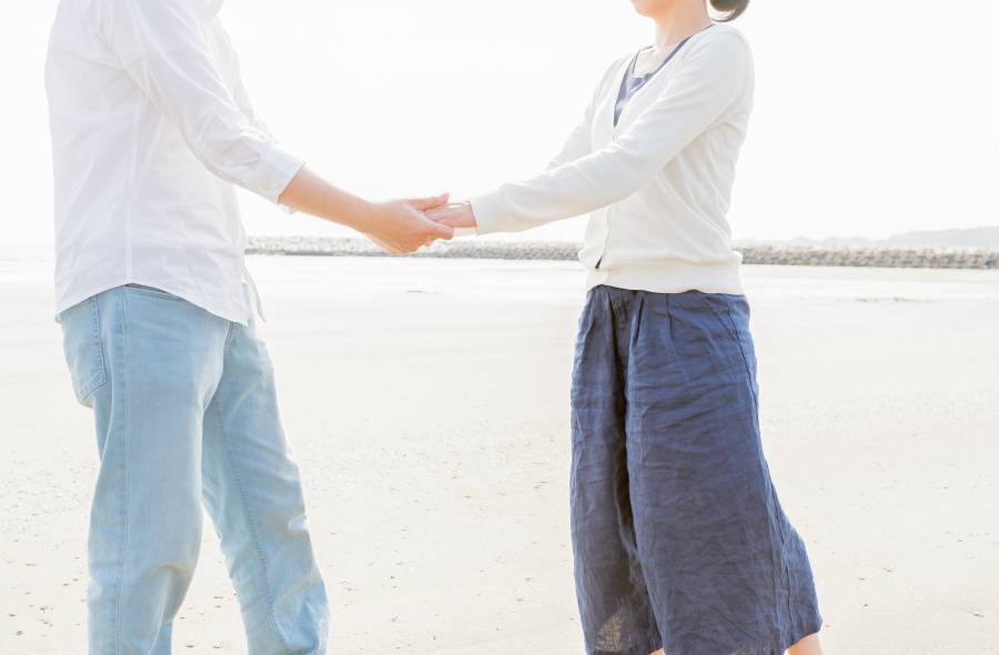 海辺でカップルが手を繋いでいる写真