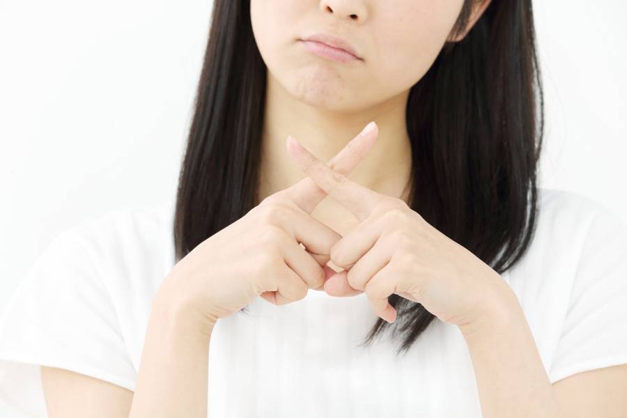 手でバツを作る女性