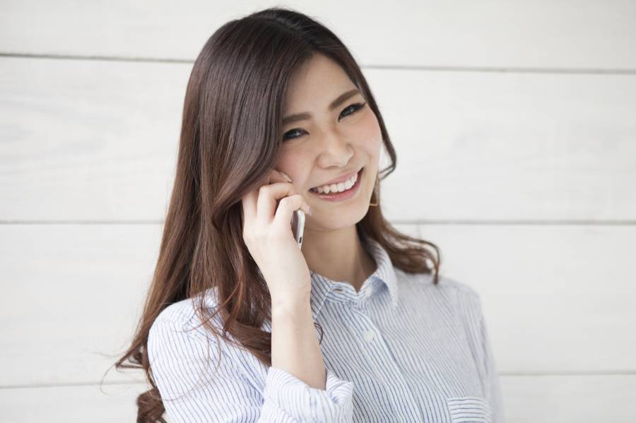 スマホ片手に笑顔で話す女性