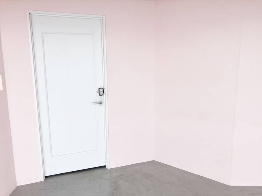 ピンクの壁と白いドア以外何もない空間