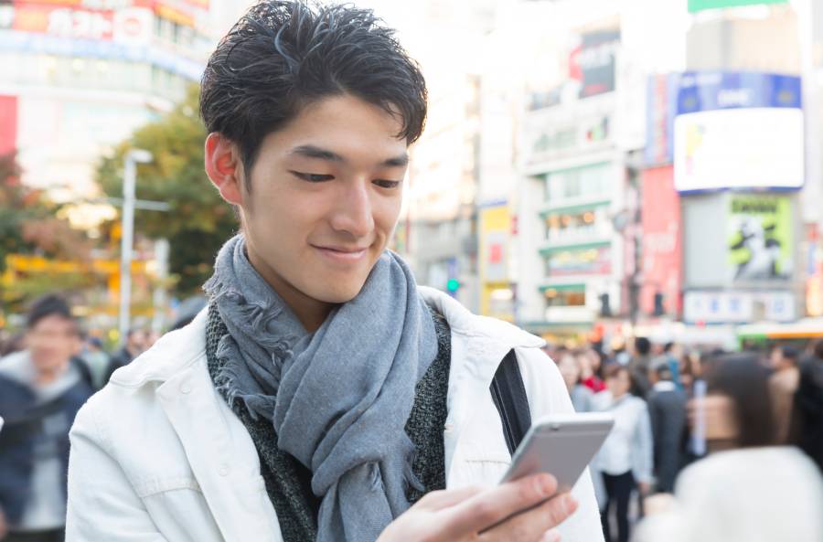 携帯電話の画面を見て笑顔を浮かべる男性